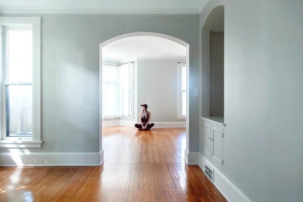 A woman in an empty house thinking about the costs associated with an empty property.