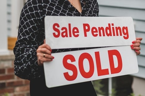 woman holding signs that say sale pending and sold